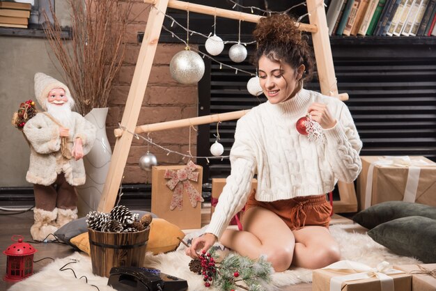 Mujer joven sosteniendo una bola roja de Navidad