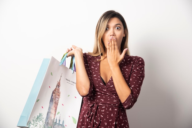 Mujer joven sosteniendo bolsas de la tienda en la pared blanca.