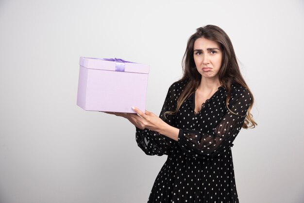 Mujer joven sosteniendo una caja de regalo púrpura