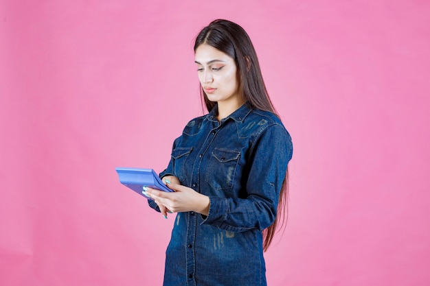 Foto gratuita mujer joven sosteniendo una calculadora azul en la mano y calculando