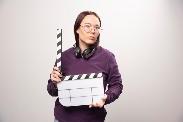 Mujer joven sosteniendo una cinta de cine sobre un fondo blanco. Foto de alta calidad