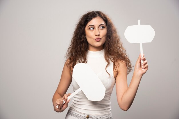 Mujer joven sosteniendo dos carteles blancos en blanco. Foto de alta calidad