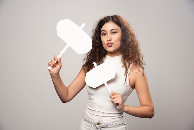 Foto gratuita mujer joven sosteniendo dos carteles blancos en blanco. foto de alta calidad