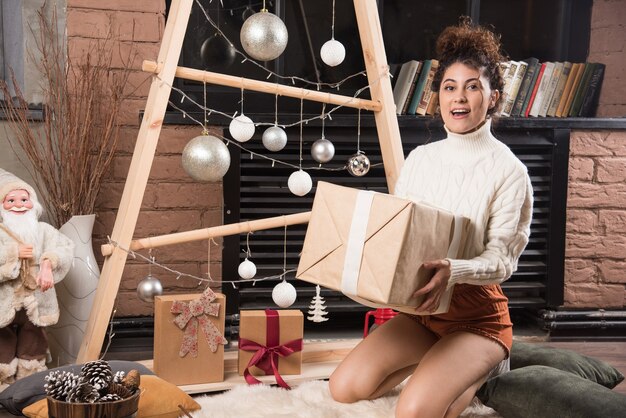 Mujer joven sosteniendo una gran caja de regalo de Navidad