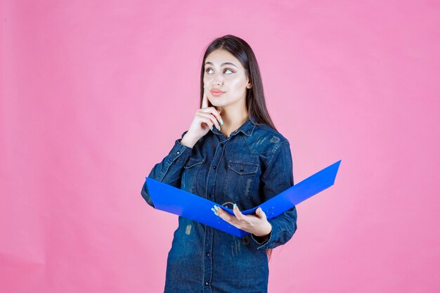 Mujer joven sosteniendo un informe empresarial y pensando