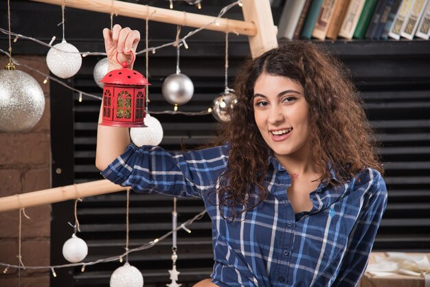 Mujer joven sosteniendo una lámpara de Navidad roja