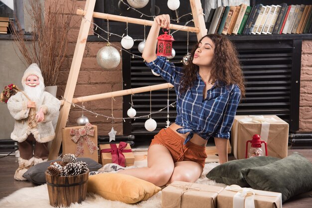 Foto gratuita mujer joven sosteniendo una lámpara de navidad roja