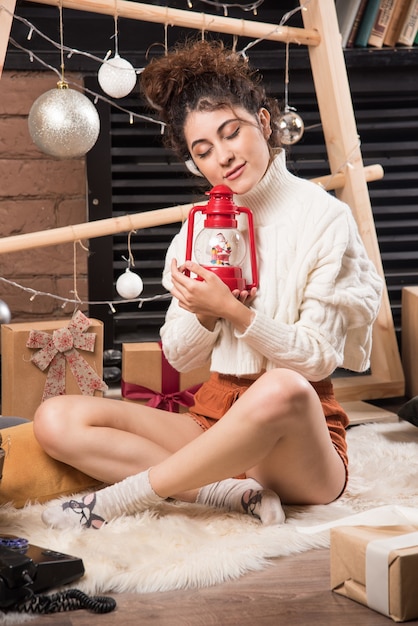 Mujer joven sosteniendo una lámpara de Navidad roja