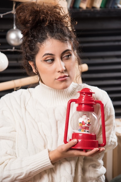 Mujer joven sosteniendo una lámpara de Navidad roja