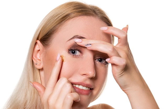 Mujer joven sosteniendo lentes de contacto en el dedo índice con espacio de copia. Cierra la cara de una mujer sana y hermosa a punto de usar lentes de contacto. Concepto de vista y oftalmología.