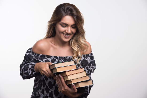 Mujer joven sosteniendo libros mientras se ríe.