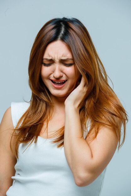 Mujer joven sosteniendo la mano en la oreja y mirando triste