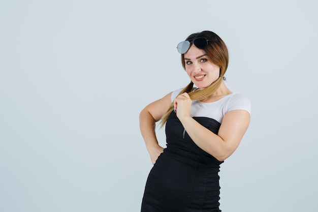 Mujer joven sosteniendo un mechón de cabello mientras sonríe