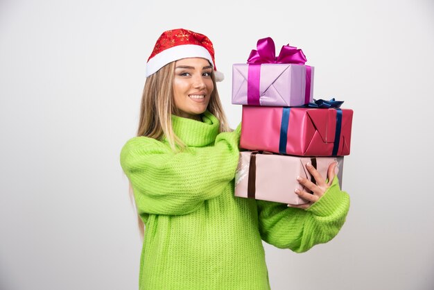 Mujer joven sosteniendo un montón de regalos navideños