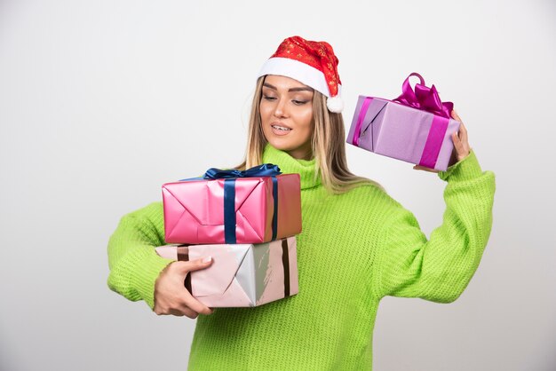 Mujer joven sosteniendo un montón de regalos navideños