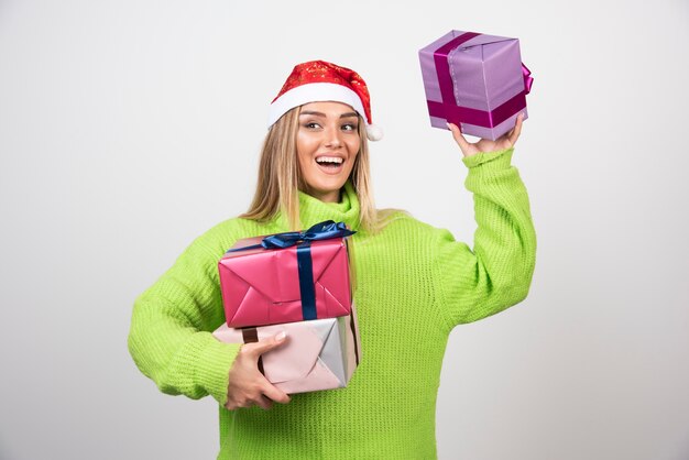 Mujer joven sosteniendo un montón de regalos navideños