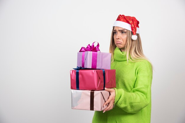 Mujer joven sosteniendo un montón de regalos navideños