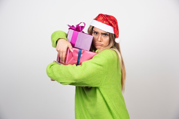 Mujer joven sosteniendo un montón de regalos navideños