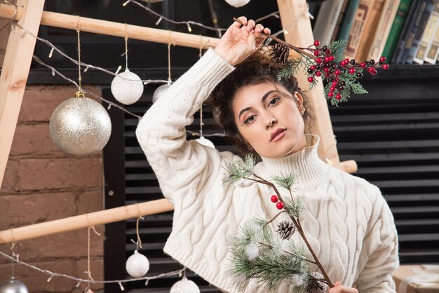 Mujer joven sosteniendo una rama de baya de acebo de Navidad