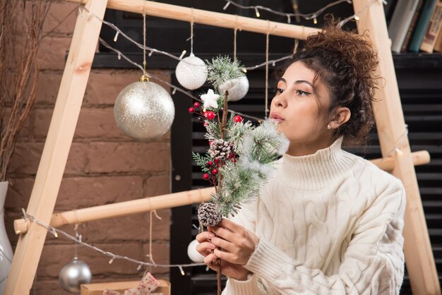 Mujer joven sosteniendo una rama de baya de acebo de Navidad
