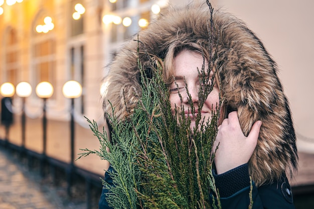 Una mujer joven sosteniendo ramas de thuja fondo borroso con luces bokeh