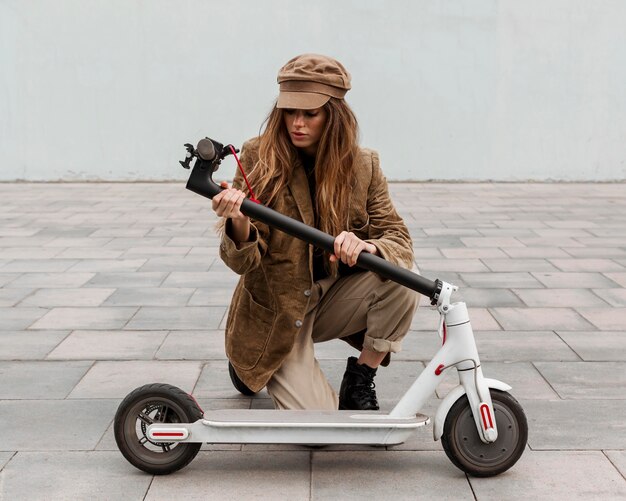 Mujer joven sosteniendo su scooter eléctrico