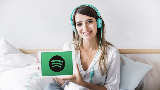 Mujer joven sosteniendo tablet con app de spotify