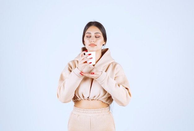 Mujer joven sosteniendo una taza de café y oliendo