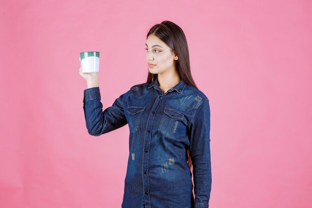 Mujer joven sosteniendo una taza de café verde blanco y oliendo