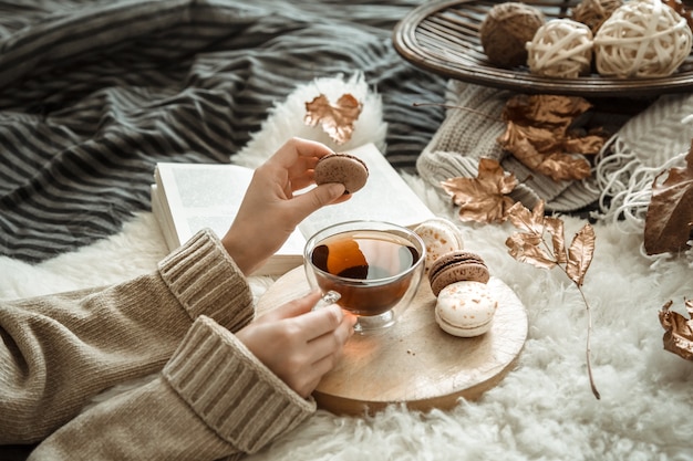 Mujer joven sosteniendo una taza de té y un macaron