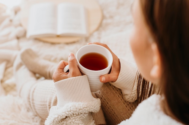 Mujer joven sosteniendo una taza de té mientras disfruta de las vacaciones de invierno