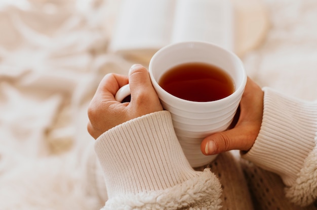 Mujer joven sosteniendo una taza de té mientras disfruta de las vacaciones de invierno