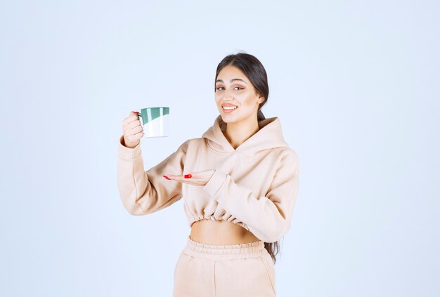 Mujer joven sosteniendo una taza verde de té o café