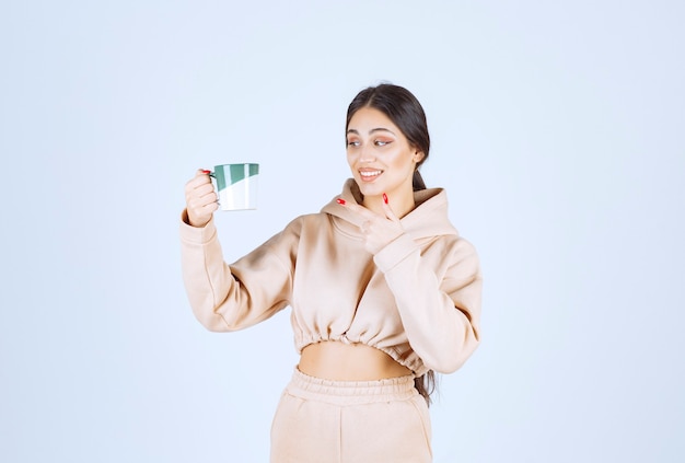 Mujer joven sosteniendo una taza verde de té o café