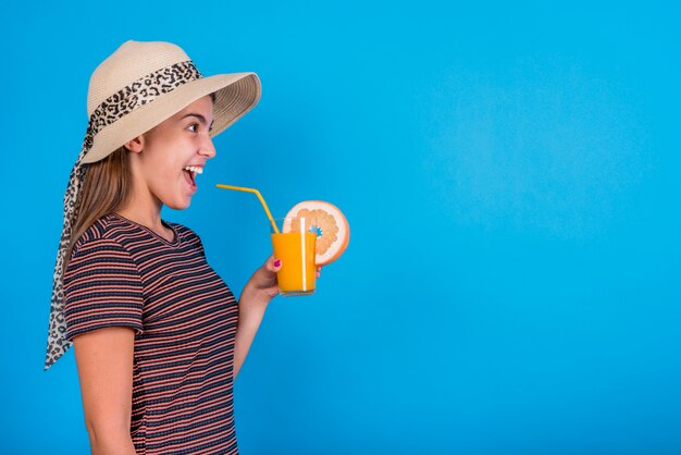 Mujer joven sosteniendo el vaso con jugo de naranja