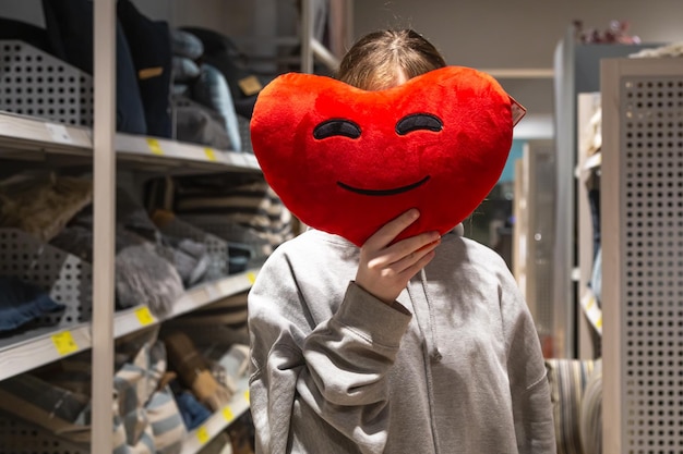 Foto gratuita una mujer joven sostiene una almohada en forma de corazón en sus manos en una tienda