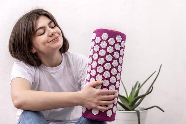 Foto gratuita una mujer joven sostiene una almohada de masaje de cuello