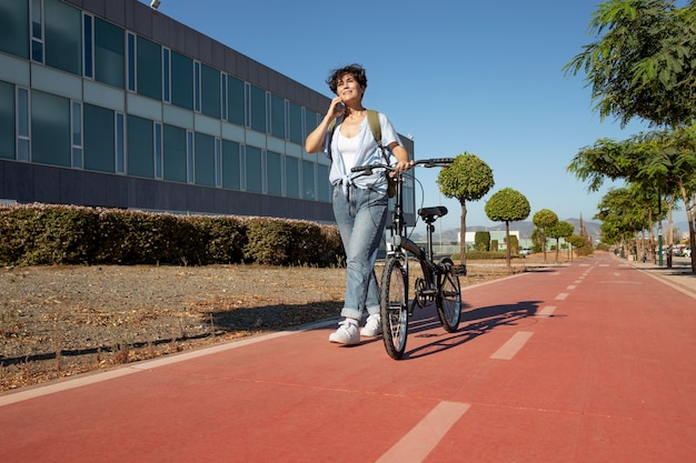 Foto gratuita mujer joven con su bicicleta plegable