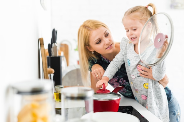 Mujer joven con su hija en la cocina