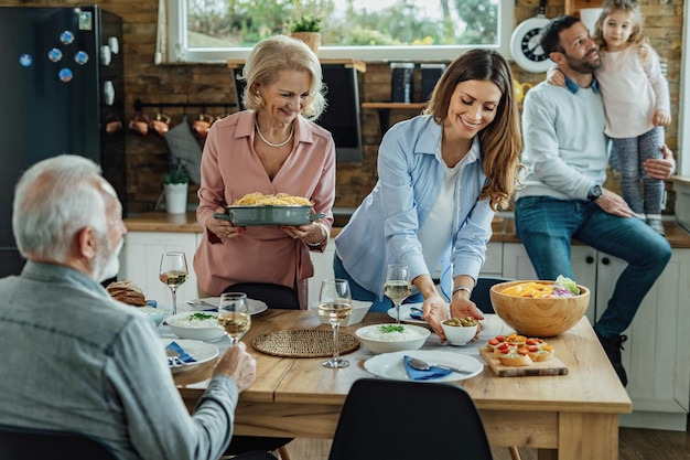 Mujer joven y su madre mayor preparando mesa de comedor para un almuerzo familiar en casa