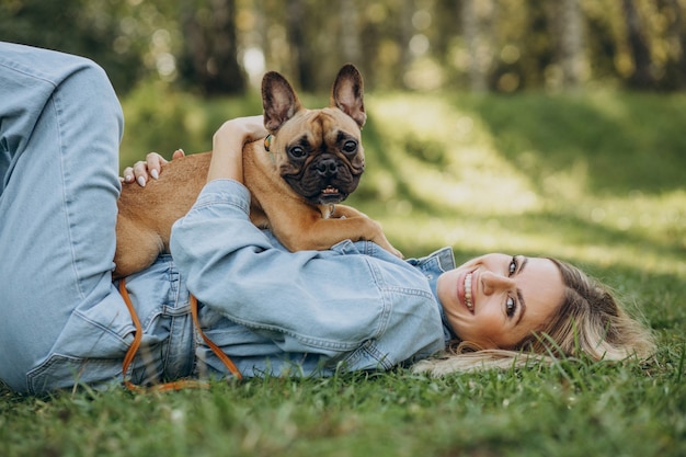 Mujer joven con su mascota bulldog francés en el parque