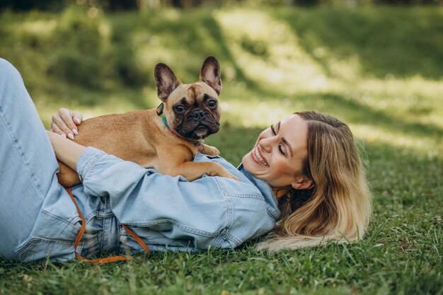 Mujer joven con su mascota bulldog francés en el parque