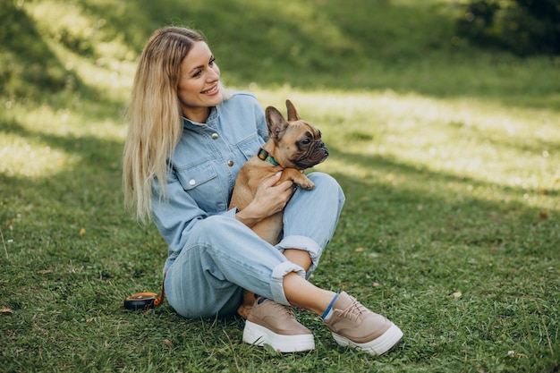 Mujer joven con su mascota bulldog francés en el parque