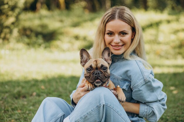 Mujer joven con su mascota bulldog francés en el parque