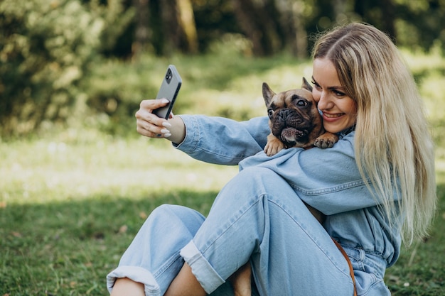 Mujer joven con su mascota bulldog francés en el parque