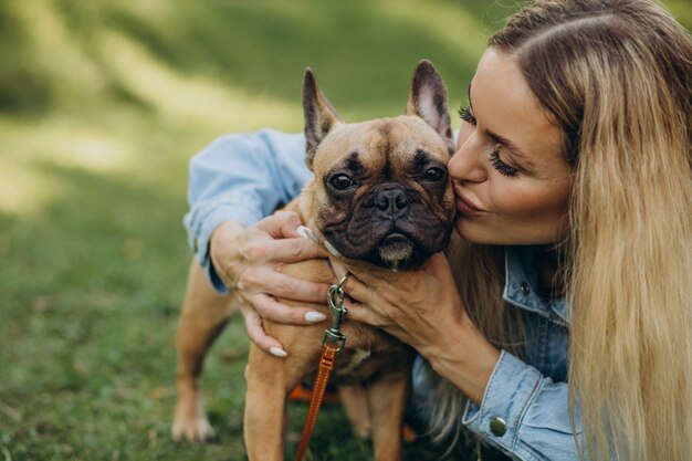 Mujer joven con su mascota bulldog francés en el parque