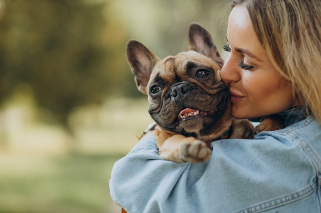 Mujer joven con su mascota bulldog francés en el parque