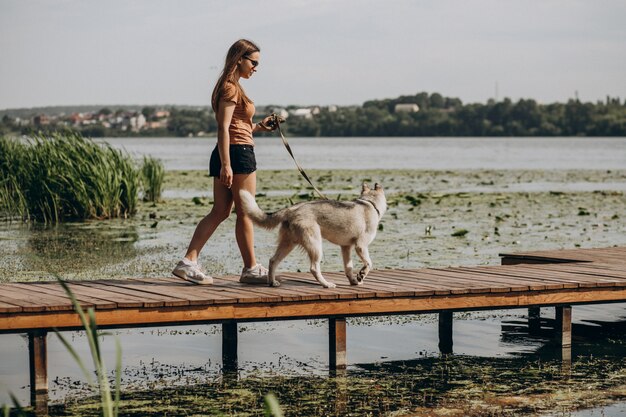 Mujer joven con su perro husky junto al lago