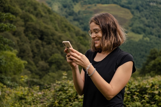 Foto gratuita mujer joven con su teléfono móvil en la naturaleza