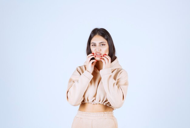 Mujer joven en una sudadera con capucha rosa asustada y asustada